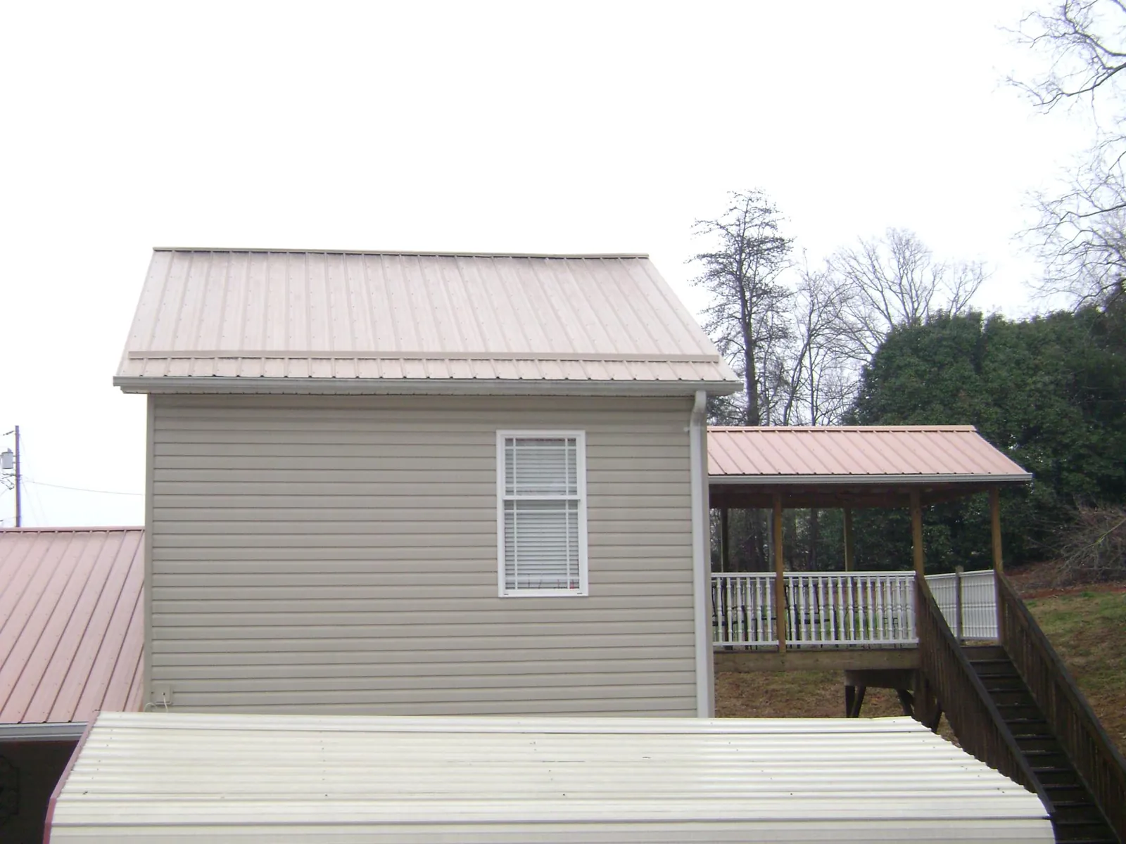 Tan metal roofs on a two story addition and attached porch, from a Roof Replacement job in Haines City