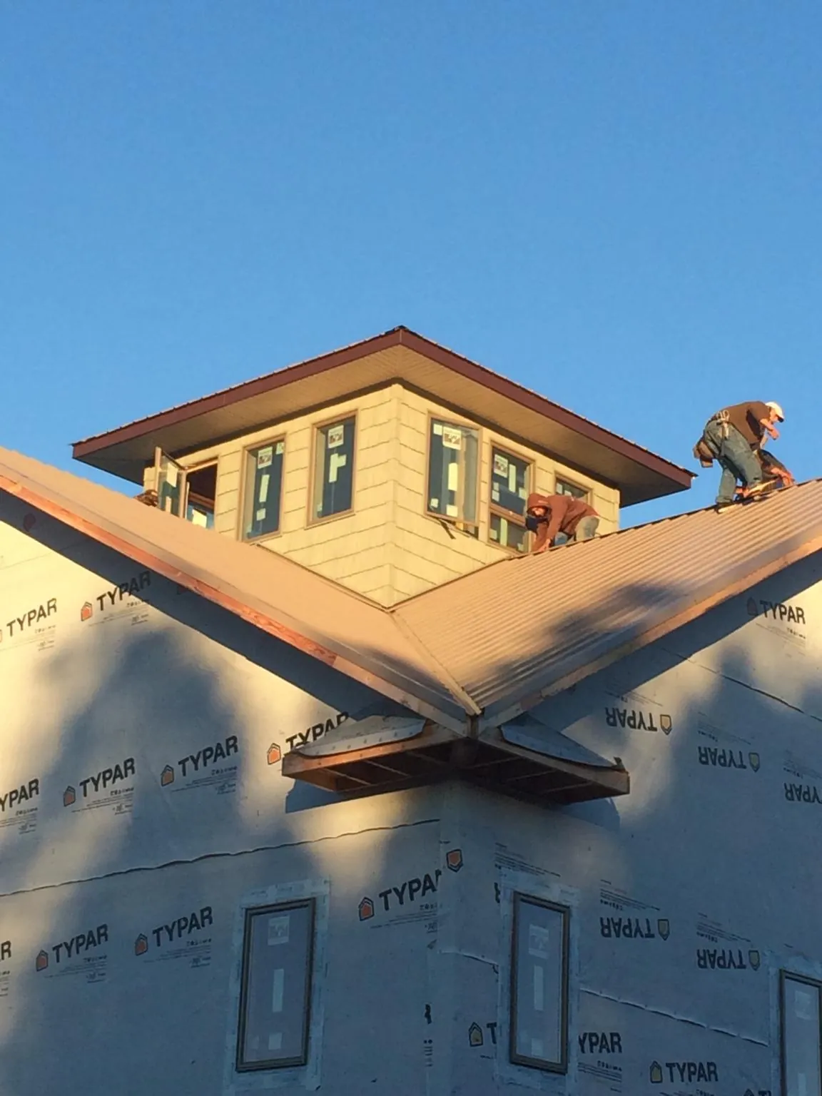 Roofers working around a rooftop cupola on a new metal roof at sunset — Roof Waterproofing in Haines City by Roofing Brothers